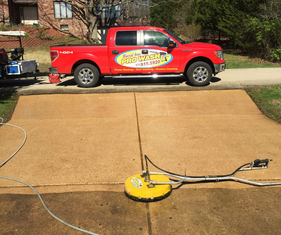 Red Pro Wash truck parked on a freshly cleaned concrete driveway in Farmington, Missouri. A surface cleaner sits mid-winter, highlighting the benefits of February pressure washing.