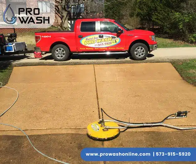 Red Pro Wash pickup parked at top of a driveway while a circular surface cleaner cleans the concrete; company logo and website visible.